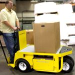 Thumbnail of http://A%20Warehouse%20Worker%20Carrying%20a%20Box%20on%20the%20Bed%20of%20a%20Yellow%20Columbia%20Stockchaser%20Inside%20a%20Warehouse